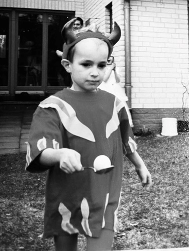 Schwarz-Weiss-Bild mit einem ca. 5-jährigen Kind im Teufel-Faschingskostüm. Das Kind macht grad Eierlauf.